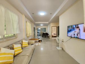 a living room with a couch and a flat screen tv at HOMEis Villa Sattahip in Ban Tao Than