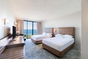 ein Hotelzimmer mit 2 Betten und einem TV in der Unterkunft Hilton Garden Inn Darwin in Darwin