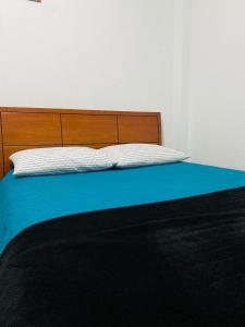 a bed with a wooden headboard and a blue blanket at Bogotá Kings 101 in Bogotá
