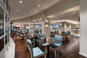 a restaurant with tables and chairs and a bar at Hilton Garden Inn Darwin in Darwin