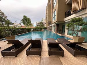 a swimming pool with chaise lounge chairs next to a building at City Garden Tropicana Condo Naklua in Pattaya North