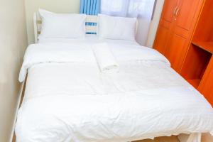duże białe łóżko z białą pościelą i poduszkami w obiekcie SYLVIA'S LUXURIOUS APARTMENT w mieście Kisumu