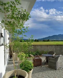 a patio with a table and chairs and trees at The White House Homestay in Pantai Cenang