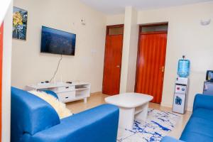 salon z niebieską kanapą i czerwonymi drzwiami w obiekcie SYLVIA'S LUXURIOUS APARTMENT w mieście Kisumu