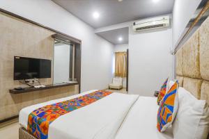 a bedroom with a bed and a flat screen tv at FabHotel Star Residency in Nagpur