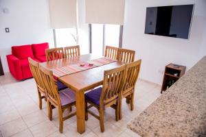 ESTE SUEÑO في سان مارتين: طاولة غرفة طعام مع أربعة كراسي وأريكة حمراء
