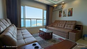 a living room with a couch and a large window at Gleem Luxury Condo Direct Sea view G18 in Alexandria