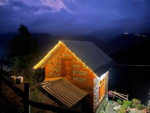 a small log cabin with lights on it at Nebula Nook Cottages in Jibhi