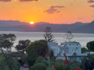 una puesta de sol de una casa con las montañas en el fondo en George Beach Studios, en Pefki