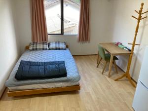 a small bedroom with a bed and a table at Midori Guesthouse&Hostel in Tsushima