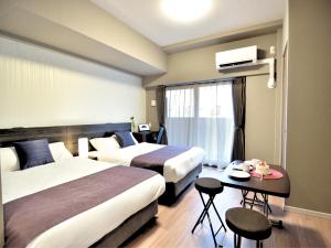 Habitación de hotel con 2 camas y mesa en BON Condominium Namba Ebisu en Osaka