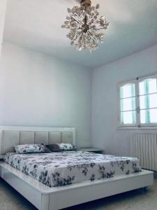 a bedroom with a bed with a chandelier at Tunis Comfort Family Home in Burj at Turkī