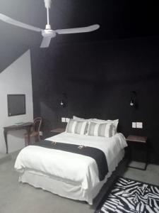 a bedroom with a large white bed with a black wall at Prosper Stud Guest House in Robertson