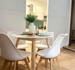 een tafel met witte stoelen en een vaas erop bij Apartamento Plaza in Castilleja de la Cuesta