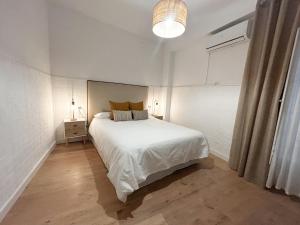 Un dormitorio con una gran cama blanca y una lámpara en Apartamento Plaza, en Castilleja de la Cuesta