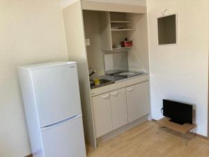 a small kitchen with a white refrigerator and a tv at Midori Guesthouse&Hostel in Tsushima