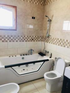 a bathroom with a bath tub and a toilet at Tunis Comfort Family Home in Burj at Turkī