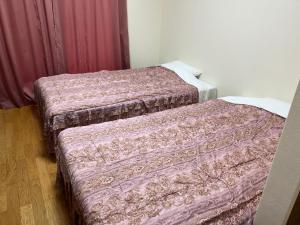2 Betten nebeneinander in einem Zimmer in der Unterkunft エスタールゴヤ in Tomari