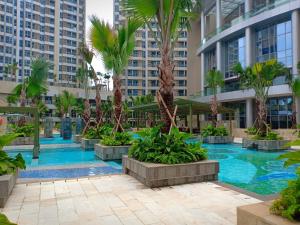 ein Pool in der Mitte eines Gebäudes mit Palmen in der Unterkunft Studio 02 Taman Anggrek Residence Best Cozy and Stay in Jakarta