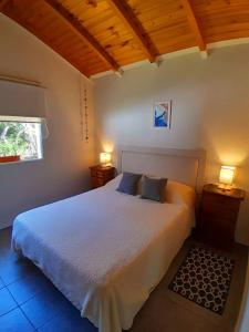um quarto com uma grande cama branca e 2 candeeiros em Casa con jardín - Circuito Chico, Bariloche em San Carlos de Bariloche