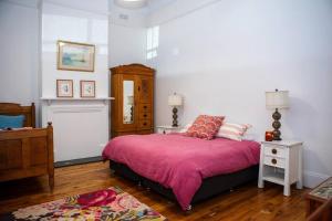 um quarto com uma cama com um cobertor rosa em Coolamon School of Arts 