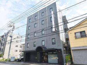 un edificio alto gris al lado de una calle en ＦＯＲＢＥＬＬ　ＳＴＡＹ　ＹＵＲＩＧＡＯＫＡ en Ikuta
