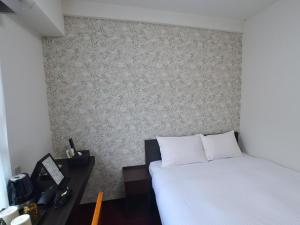 ein Schlafzimmer mit einem weißen Bett und einer Wand in der Unterkunft ＦＯＲＢＥＬＬ　ＳＴＡＹ　ＹＵＲＩＧＡＯＫＡ in Ikuta