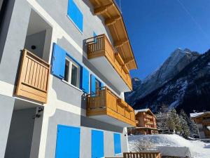 a building with blue windows with mountains in the background at Ciamorc Relax & Sport Appartament for max 2 Adults 1 child 1 infant in Canazei