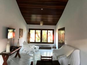 una sala de estar con muebles blancos y techo de madera. en Casa Pirambu, en Pipa