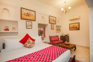 a bedroom with a red bed and a chair at Amritara Chandra Mahal Haveli, Bharatpur in Bharatpur