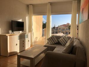 a living room with a couch and a large window at Limnaria Gardens - 1 bedroom, sunny apartment with stunning pool views in Paphos City
