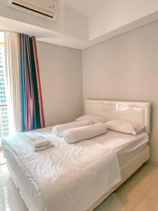 een slaapkamer met een bed met witte lakens en een raam bij Studio 17 Taman Anggrek Residence Best Cozy and Stay 50mbps Wifi in Jakarta