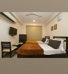 um quarto com 2 camas, uma cadeira e uma televisão em Hotel singh palace em Jaipur