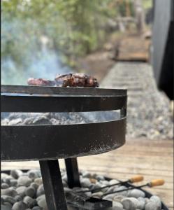 una griglia con carne sopra di essa, accanto a una panchina di Casa Gallareta , luxury con costa del lago . a Villa La Angostura