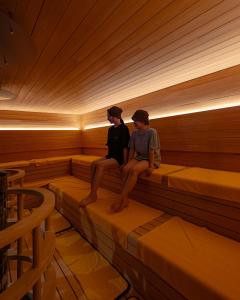 dos personas sentadas en el interior de una sauna en KAMOME SLOW HOTEL the COMPACT en Awaji