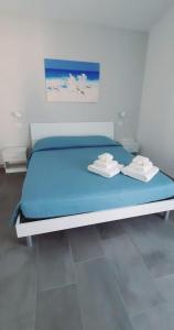 a bed in a room with blue sheets and towels at Casa Olla in Quartucciu