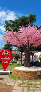 uma árvore com flores cor-de-rosa ao lado de um cartaz em PloyPhailin พลอยไพรินรีสอร์ท em Ko Larn