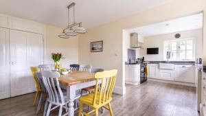 a kitchen and dining room with a wooden table and yellow chairs at Trelawney Cottage - sleeps 8 - near Wadebridge in Saint Wenn