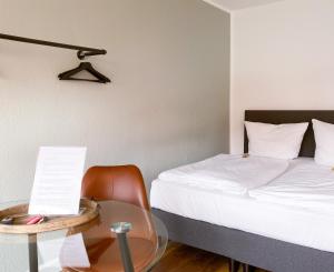 a bedroom with a bed and a glass table with a chair at Apartment Neuss-Düsseldorf Messe in Neuss