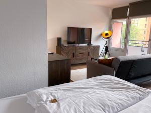 a bedroom with a bed and a tv and a couch at Apartment Neuss-Düsseldorf Messe in Neuss