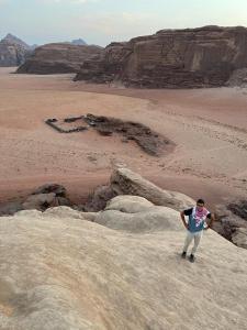 un hombre parado en algunas rocas en el desierto en Bedouin Tours Camp, en Wadi Rum