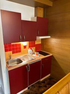 a small kitchen with red cabinets and a sink at RELAX Seefeld Apartman in Seefeld in Tirol