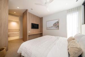 a bedroom with a white bed and a tv at Oceano Residence Mornington in Mornington