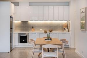 a kitchen with white cabinets and a table and chairs at Apartment Living on the Beach in Rosebud