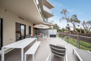 an outdoor patio with a white table and chairs at Apartment Living on the Beach in Rosebud