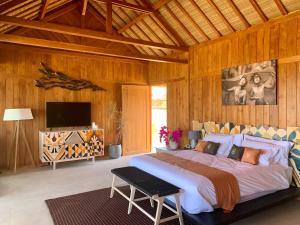 een slaapkamer met een groot bed en een televisie bij Lobster Bay Lombok in Awang