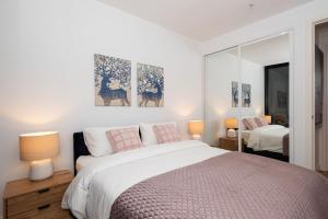 Bayside living at The Hampton في ملبورن: غرفة نوم مع سرير كبير مع وسائد وردية