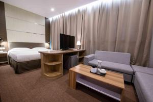 a hotel room with a bed and a couch at Hotel Meliden in Sandakan