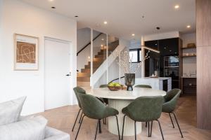 une cuisine et une salle à manger avec une table blanche et des chaises vertes dans l'établissement Sport Precinct Luxury Style over four levels, à Melbourne