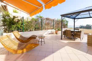 un patio con sillas, una mesa y una sombrilla en BEAUSEJOUR - PISCINE - PARKING - Monaco en Beausoleil